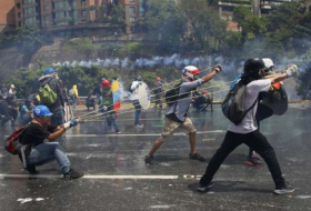 Venezuelans battle tear gas with shields, masks, feces bombs